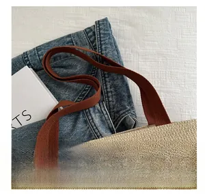 Detail of striped woven tote bag handle and textured fiber weave against denim fabric