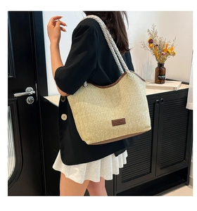 Large woven straw beach tote bag with rope handle shown on model for vacation style