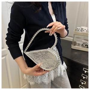 Detailed view of silver heart-shaped evening bag with sparkling rhinestone embellishments