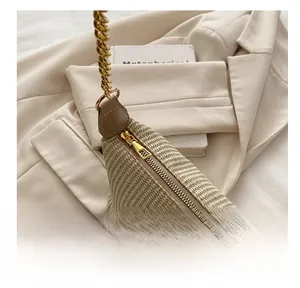 Gros plan détaillé du sac tressé beige avec fermeture éclair dorée et bandoulière chaîne