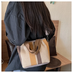 Detailed side view of a large striped tote bag with woven texture and crossbody strap