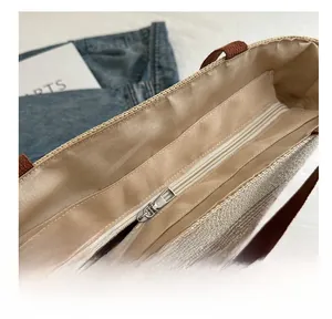 Detail of smooth metal zipper and silk lining inside the striped straw tote bag