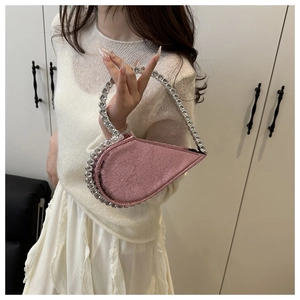 Detailed shot of pink heart-shaped bag with sparkling rhinestone handle and pleated texture