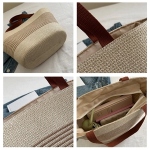 Detail view of large straw tote bag with striped handles and spacious zip interior