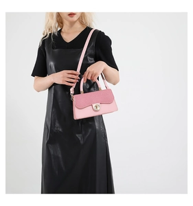 Sac bandoulière rose avec boucle dorée et bandoulière en cuir porté par mannequin