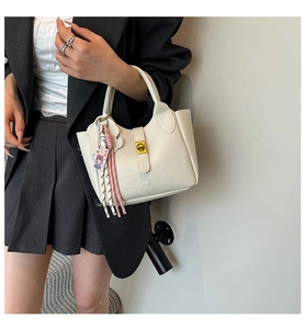 Elegant white lychee pattern bucket bag with gold clasp shown on a model in a blazer.