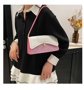 Detail of stylish contrast handbag featuring pink glitter panel and golden twist lock