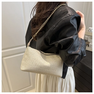 Détail d'un sac à main tissé texturé vertical avec bandoulière en chaîne dorée chic