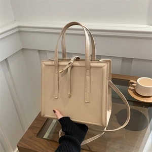 Minimalist cream tote bag with elegant knot detail and detachable crossbody strap