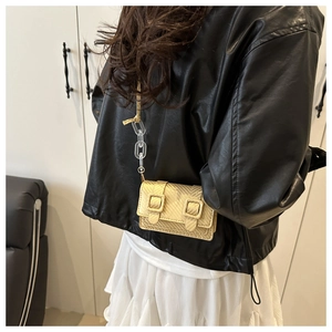 Detail of gold mini crossbody bag with woven texture and transparent resin chain strap