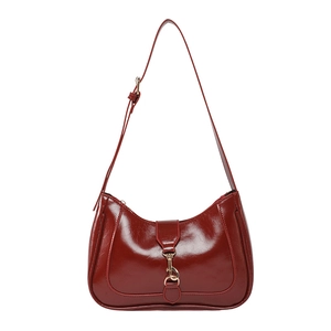 Sac sous le bras en cuir verni bordeaux brillant avec boucle dorée sur fond blanc