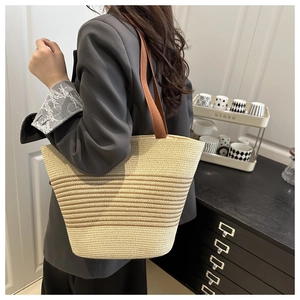 Detail shot of a beige striped woven cotton rope tote bag with brown handles on a model