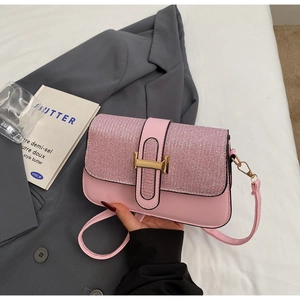 Detail of pink patchwork crossbody bag featuring glitter texture and golden H-shaped clasp