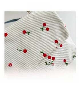 Vue détaillée du tissu en velours côtelé blanc avec broderie de cerises rouges sur le sac