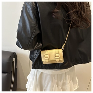 Detail of a golden textured mini crossbody bag featuring a chic flap and dual buckle accents