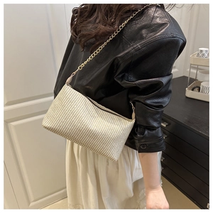 Détail du sac bandoulière en paille tissé main avec rayures et chaîne dorée fine