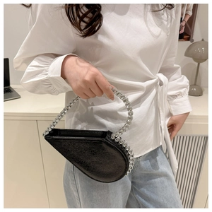 Detail of black heart-shaped evening clutch bag with sparkling diamond-encrusted round handle