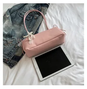 Minimalistische rosa Unterarmtasche mit dekorativer Perle-Schleife auf weißem Stoff