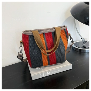 Détail d'un sac cabas tissé à rayures avec poignées marron et une bandoulière réglable
