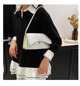 Detail of white and silver glitter shoulder bag with golden twist lock and braided trim