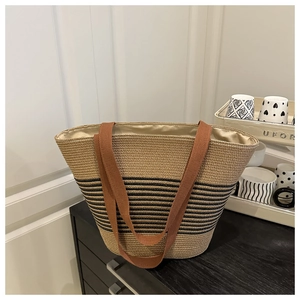 Detail of hand-woven tote bag with black stripes, fabric handles and gold lining
