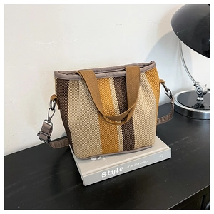 Détail d'un sac cabas en tricot rayé avec textures de tissu marron et jaune et sangle