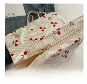 Détail de la fermeture éclair et du motif cerise sur le sac en velours côtelé