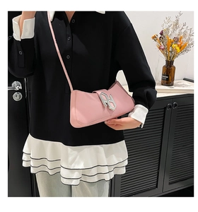 Détail du sac sous le bras en similicuir rose avec boucle argentée et fine bandoulière