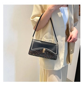 Detail of glitter patchwork and wave stitching on a black leather underarm bag