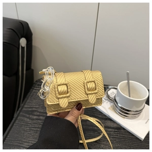 Detail of woven texture mini crossbody bag with golden finish and clear acrylic chain