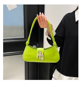 Détail du sac bandoulière en similicuir vert fluo avec logo métallique et poignée nouée