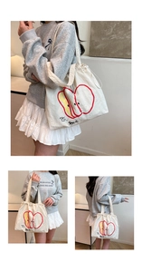 Detail of white nylon tote bag showing drawstring closure and red apple print design
