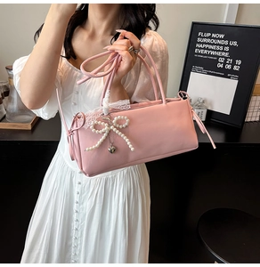 Sweet pink underarm bag for women with pearl bow and lace detail held by model