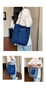 Detail of a reversible canvas tote bag showing the dark blue side and woven shoulder strap