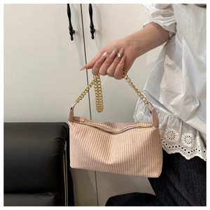 Détail d'un sac à main tissé rose avec une grosse chaîne dorée et une fermeture éclair