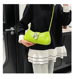 Détail du sac sous l'aisselle en cuir vert fluo avec boucle géométrique en métal argenté
