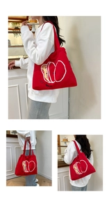 Detail of red drawstring nylon tote bag featuring a minimalist white apple line art print