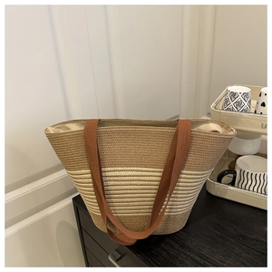 Detail of two-tone woven tote bag showing dark brown and beige textures on wood surface