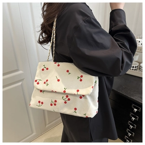 Détail du sac bandoulière en velours côtelé avec motifs cerises et chaîne dorée