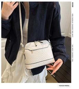 Détail de la texture tressée blanche et de la fermeture éclair dorée du sac bandoulière