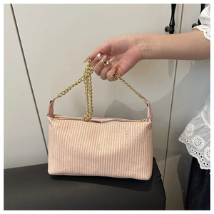Détail du sac à main tissé rose avec bandoulière dorée et motif à rayures verticales