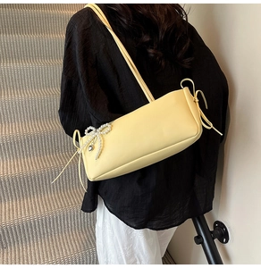 Sweet yellow underarm bag with pearl heart charm and bow detail worn by model