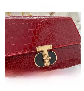 Detail of red crocodile texture handbag with gold T-shaped clasp and chain strap