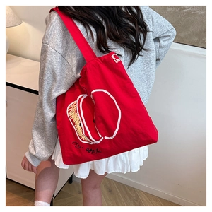 Detail of red canvas tote bag featuring white apple print and handwritten text