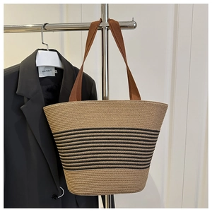 Detail of the woven tote bag showing black stripes and wide brown fabric shoulder strap