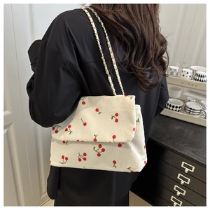 Détail du sac cabas en velours blanc à motif cerise avec bandoulière chaîne en métal