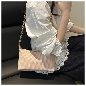 Sac bandoulière rose tissé avec chaîne dorée présenté porté à l'épaule