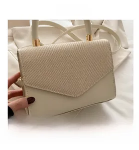 Close-up of cream white PU leather handbag featuring straw texture and gold hardware