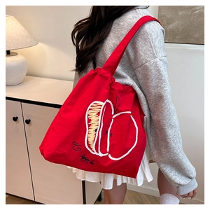 Detail of red canvas tote bag featuring an artistic apple print and spacious interior