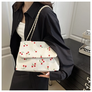 Détail du sac cabas en velours côtelé avec motif cerise et chaîne dorée sur un mannequin